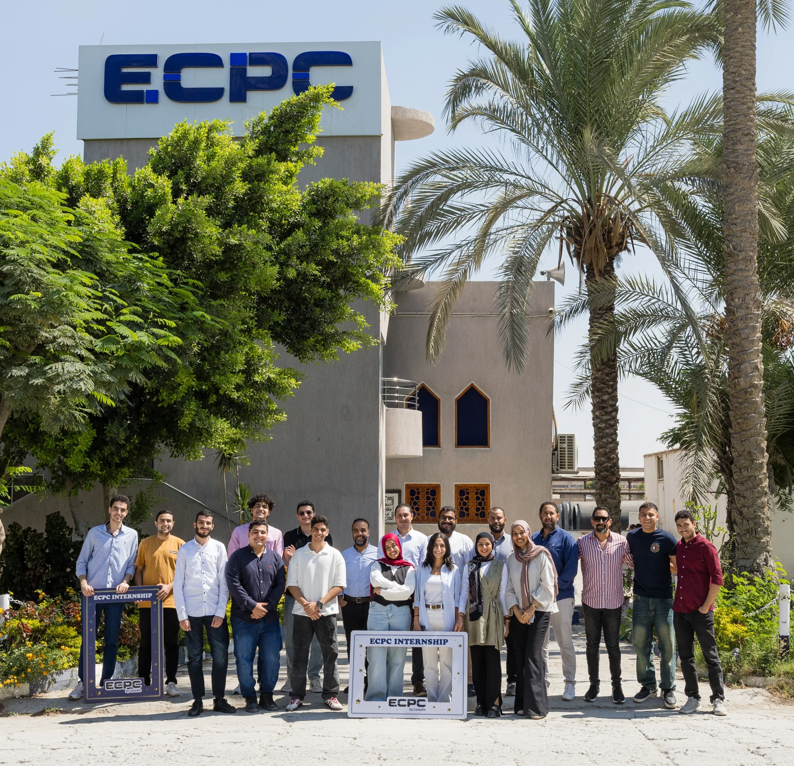 Group photo of ECPC internship students and staff in front of the ECPC building under sunny skies.