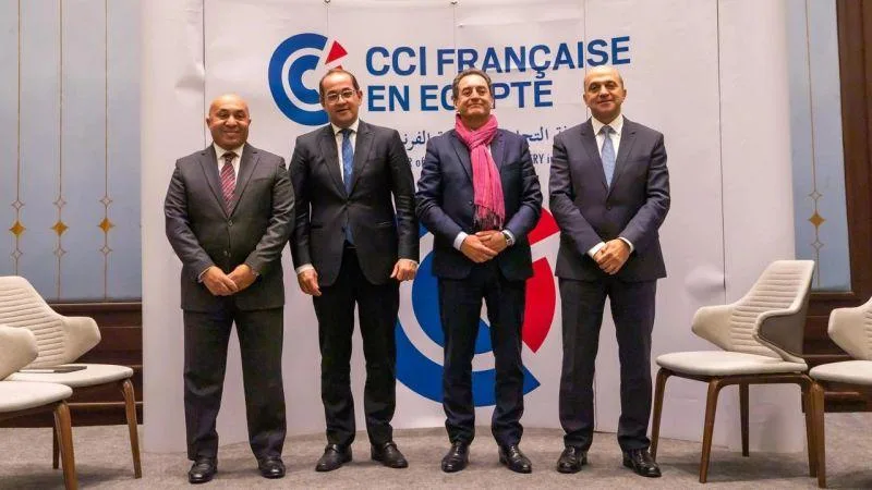 ECPC Precast Concrete executives with Minister of Finance at CCIFE forumFormal group photo of four men in business suits, including Egypt's Minister of Finance Ahmed Kouchouk (second from left), standing in front of a large white CCI Française en Égypte backdrop.