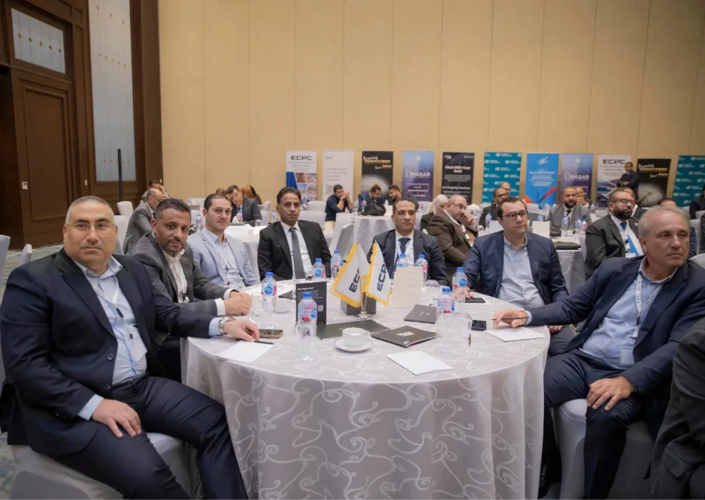 A group of ECPC industry leaders and executives seated at a conference table featuring ECPC table flags during a high-level business forum organized by the French Chamber of Commerce (CCIFE) in Egypt.