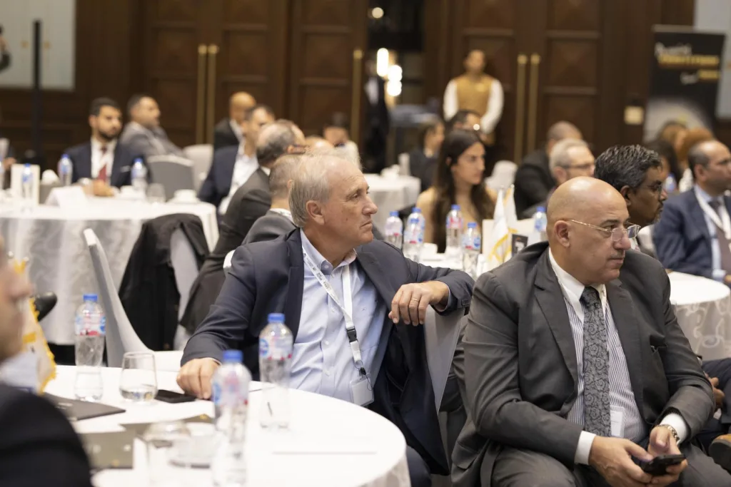 ECPC leaders and other professional delegates seated at round tables, listening to a presentation during the CCIFE high-level business meeting.